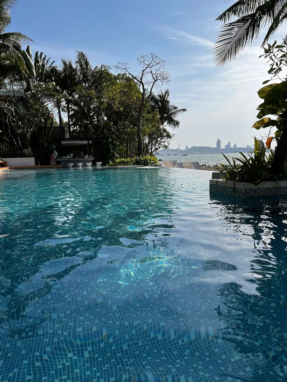 Palm-fringed swimming pool overlooking the sea in Pattaya; destination inspiration.